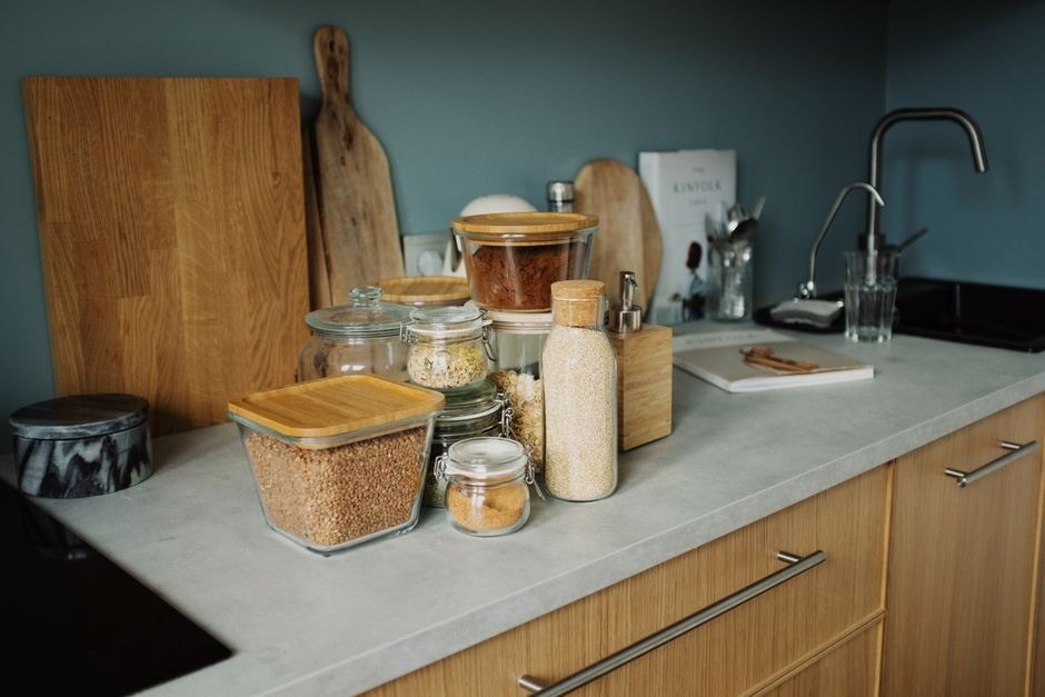 Wooden kitchen counter with jars, boards and everyday ingredients