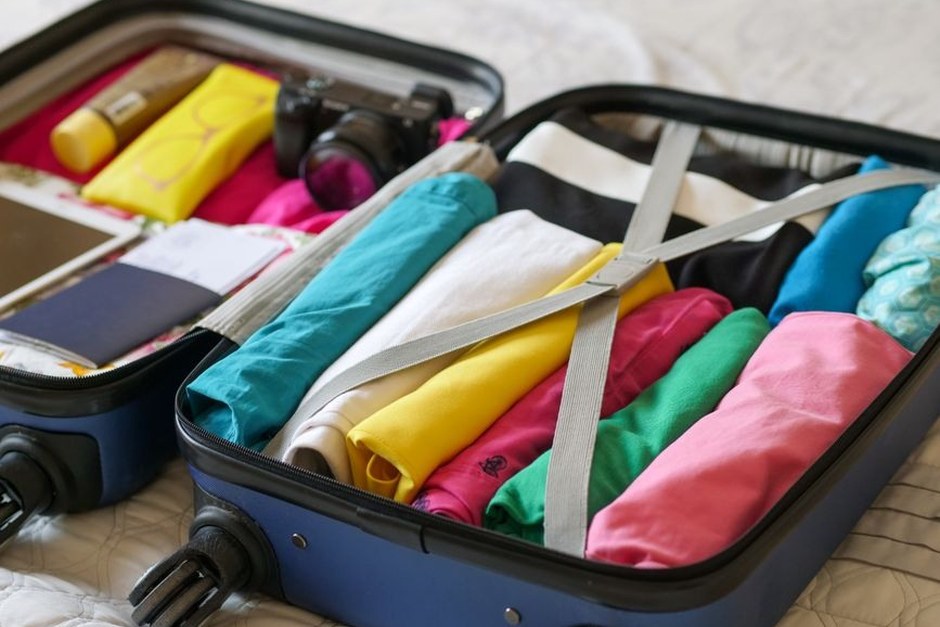 Open suitcase packed neatly with rolled colorful clothing